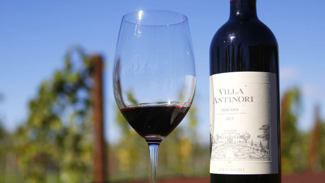 
                    A glass and bottle of Villa Antinori Toscana 2013 red wine, produced by Marchesi Antinori SpA, sit on display in this arranged photograph at the Antinori vineyards around San Casciano in Val di Pesa, Tuscany, Italy
                